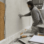 Ouvrier applique crepi isolant sur mur exterieur