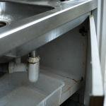 Canalisation qui pue : évier, siphon et dépôts gras visibles sous l’évier